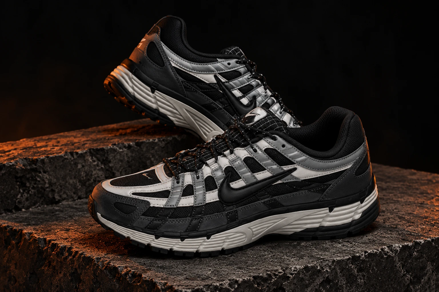 Black and silver running sneakers in a dark studio setting